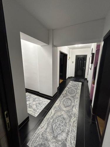 a hallway with white walls and a rug on the floor at Apartament de 3 camere zona Obcini in Suceava