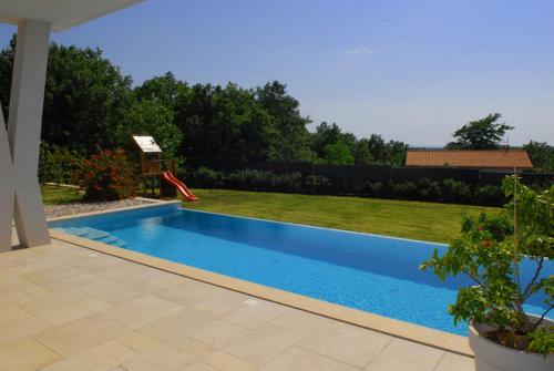 une piscine dans un jardin avec un toboggan rouge dans l'établissement Villa Astera near Poreč for 8 people with infinity pool, whirlpool & sauna, à Višnjan