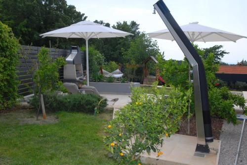 un jardin avec deux parasols blancs dans une cour dans l'établissement Villa Astera near Poreč for 8 people with infinity pool, whirlpool & sauna, à Višnjan