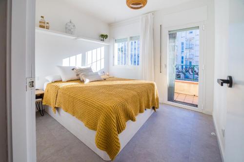 a white bedroom with a bed with a yellow blanket at La Calma in Platja  d'Aro