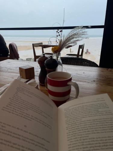 a book on a table with a cup and a coffee mug at Holywell View 30 in Cubert