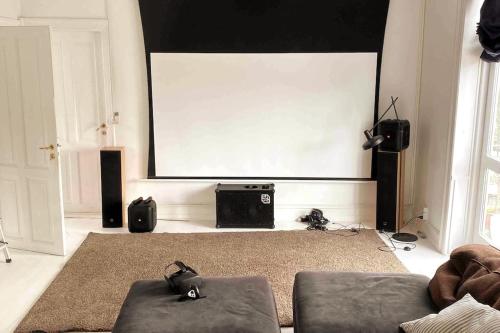 a living room with a large screen in front of a stage at Copenhagen Open Plan House in Hellerup in Hellerup