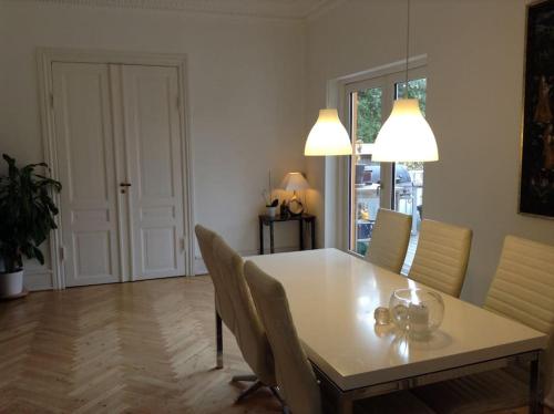 une salle à manger avec une table et des chaises blanches dans l'établissement Copenhagen Open Plan House in Hellerup, à Hellerup