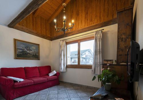 a red couch in a living room with a window at Au Petit Chevrot in Aosta