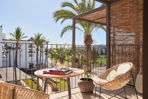 een balkon met een tafel en stoelen en palmbomen bij La Zambra Resort GL, part of The Unbound Collection by Hyatt in Mijas