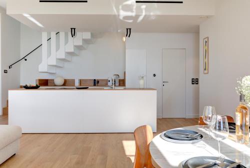 - une cuisine et une salle à manger avec des murs blancs et une table dans l'établissement IMMOGROOM - Apparements luxueux - 2min du Palais - Vue mer - Clim, à Cannes