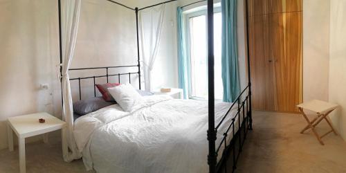 een slaapkamer met een zwart hemelbed en een raam bij trullo contemporaneo in Serranova