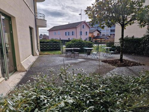 un patio con una mesa y un árbol y un edificio en Appartement confortable - Proche du lac, en Divonne-les-Bains