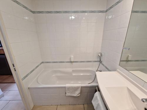 Baño blanco con bañera y lavamanos en Appartement confortable - Proche du lac, en Divonne-les-Bains