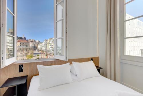 una camera da letto con un letto e due finestre di IMMOGROOM - Appartements luxueux - 2min du Palais - Vue mer - Clim a Cannes