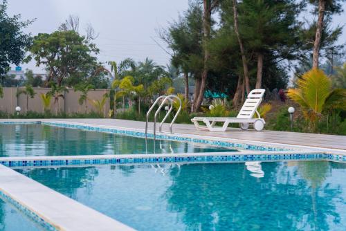 a swimming pool with a chair and a bench next to it at Hotel Nilkantha in Mandarmoni