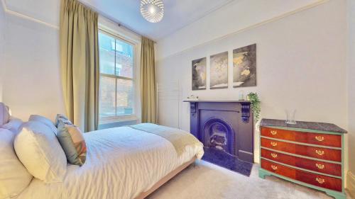 ein Schlafzimmer mit einem Bett, einem Kamin und einer Kommode in der Unterkunft Bright & Spacious West London Gem in London