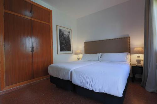 a bedroom with a large bed and a wooden cabinet at Hotel Tugasa El Almendral in Setenil