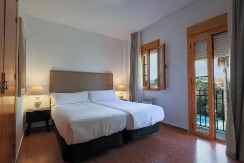 a bedroom with a large bed and a window at Hotel Tugasa El Almendral in Setenil
