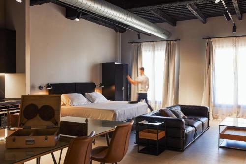 a man in a room with a bed and a couch at HO Paseo de Almería in Almería