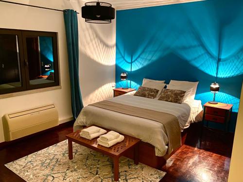 um quarto com uma cama com uma parede azul em Casa Calidris - Bed, Wine & Breakfast em Sesimbra