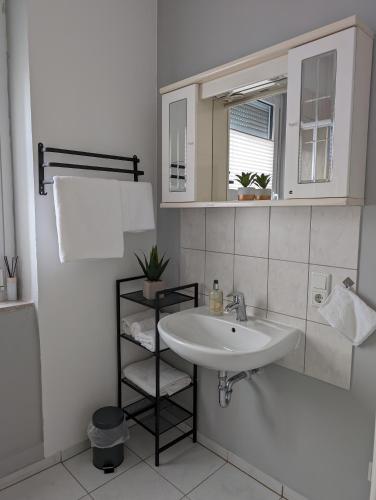 a white bathroom with a sink and a mirror at Ferienwohnung am Theater 2 in Schweinfurt