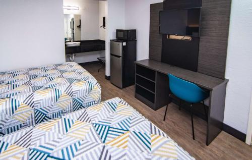 ein Hotelzimmer mit einem Bett und einem Schreibtisch mit einem TV in der Unterkunft Motel 6-Ft. Pierce, FL in Fort Pierce