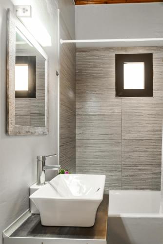 a bathroom with a white sink and a tub at Dada's Cottage in Argyrádes