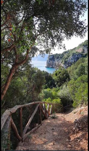 a wooden bridge on a hill with a view of the ocean at Appartamenti Manuela in Cala Gonone
