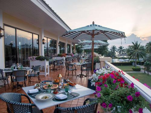 un patio con tavoli, sedie e ombrellone di Sofitel Krabi Phokeethra Golf and Spa Resort a Klong Muang Beach