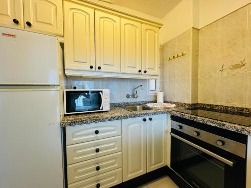 a kitchen with a white refrigerator and a microwave at Cosy Apartment in the heart of Las Americas in Arona
