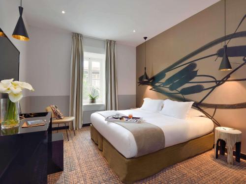a hotel room with a large bed and a desk at Hôtel & Spa Jules César Arles - MGallery Hotel Collection in Arles