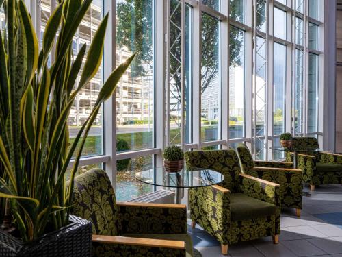 eine Lobby mit Stühlen, einem Tisch und Fenstern in der Unterkunft Mövenpick Hotel Nürnberg Airport in Nürnberg