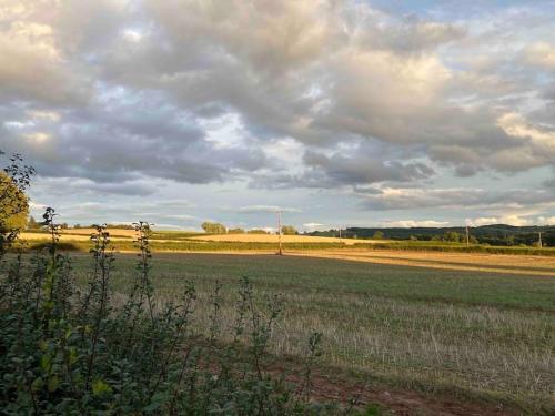 un campo vacío con un cielo nublado en la distancia en Meadow Barn, en Hereford