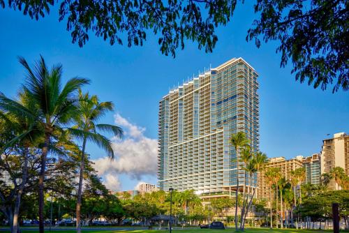 a tall building with palm trees in front of it at Ka Laʻi Waikiki Beach, LXR Hotels & Resorts in Honolulu