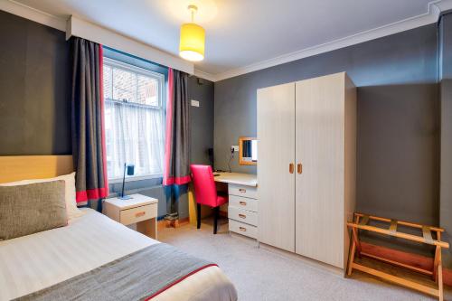 a bedroom with a bed and a desk and a chair at The Derby Conference Centre and Hotel in Derby