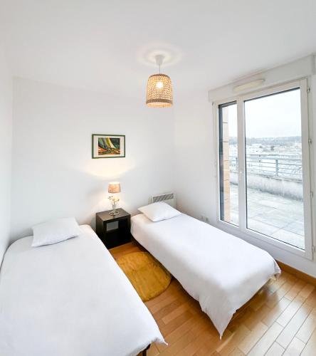 deux lits dans une chambre avec une fenêtre dans l'établissement La Douce Évasion à 13 minutes du château de Versailles, à Saint-Cyr-lʼÉcole