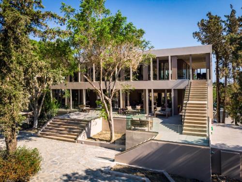 a building with stairs and trees in front of it at White Olive Premium Lindos in Pefki Rhodes