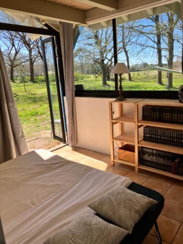 un lit dans une chambre avec une grande fenêtre dans l'établissement Havre de paix à 15 km des plages, à Soustons