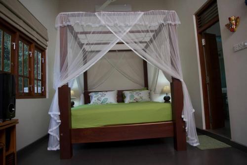 a bedroom with a canopy bed with green sheets at Koratuwa - Dickwella in Dickwella