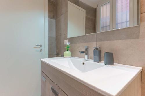 uma casa de banho com um lavatório branco e um espelho. em Sette Chiese Apartments em Bolonha