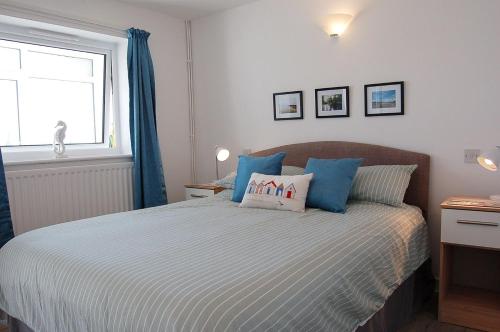 a bedroom with a bed with blue pillows and a window at Sunny Side Up Beach House in Tywyn in Tywyn