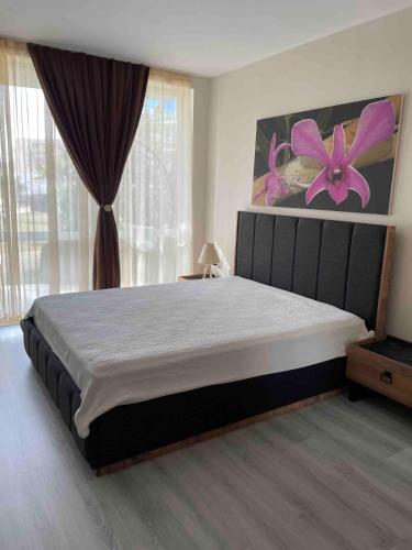ブルガスにあるApartament Ivanovi 119のベッドルーム1室(紫色の花が壁に飾られた大型ベッド1台付)
