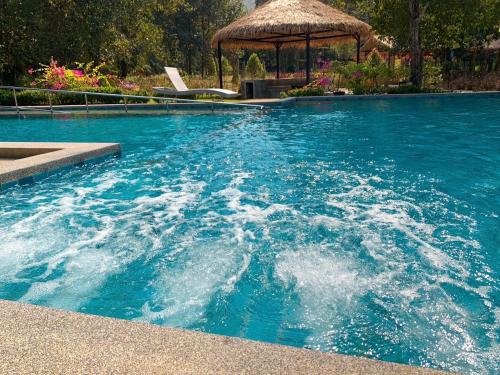 una piscina de agua azul con cenador en Baan Pingkan Wellness Resort, en San Kamphaeng