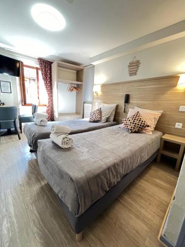 a hotel room with two beds in a room at Hôtel Du Cheval Blanc in Barcelonnette