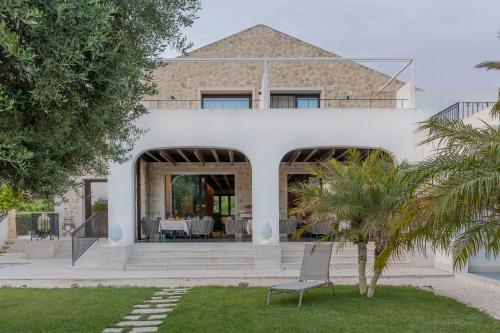 una casa blanca con una palmera en el patio en Borgo Giallonardo Wine Relais en Realmonte