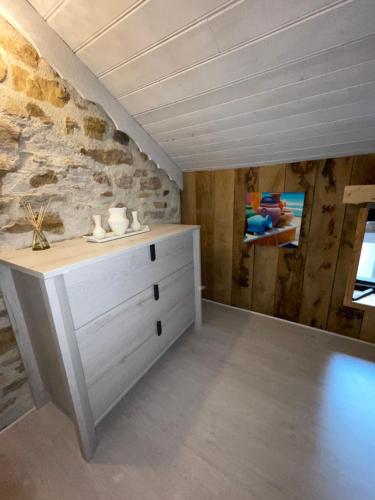 Habitación con vestidor blanco y pared de piedra. en Séjour à la Marronnie en Saint-Germain-les-Vergnes