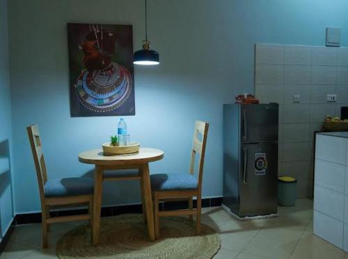 Una cocina con mesa y sillas y un refrigerador. en ILBORU HAVEN HOMEs, en Arusha