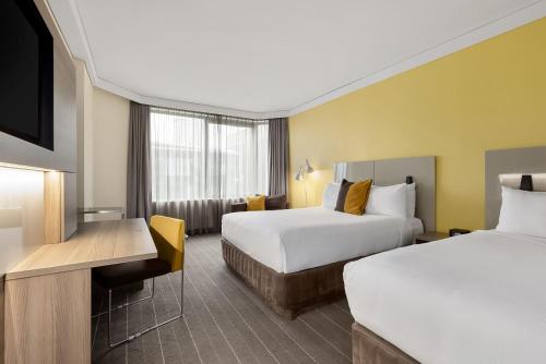 a hotel room with two beds and a desk at Sydney Central Hotel managed by The Ascott Limited in Sydney