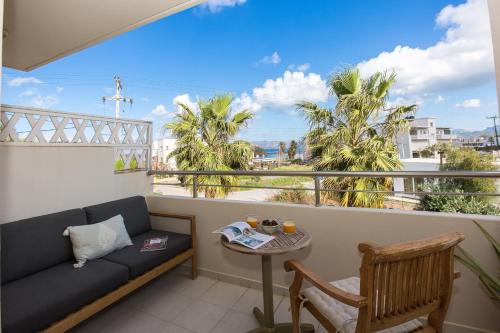 a balcony with a couch and a table and palm trees at Arodamos Studios & Apts in Kissamos