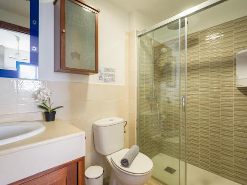 a bathroom with a toilet and a glass shower at Casa Joral, para surfear en Famara in Famara