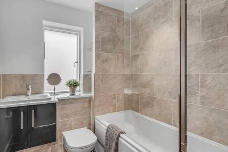 a bathroom with a tub and a toilet and a sink at 2 bedroom house NE Norwich in Norwich