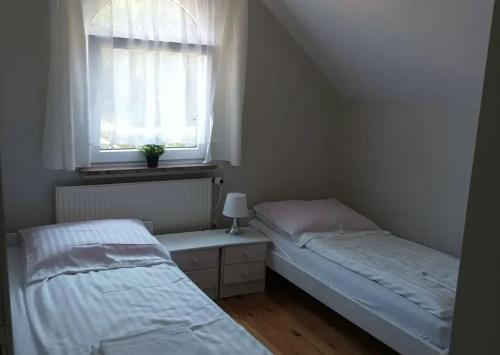 Duas camas num pequeno quarto com uma janela em Dom Lidia em Poddabie