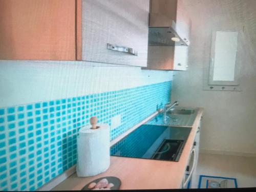 カステルサルドにあるCastelsardoの青いタイルの壁のキッチン、シンクが備わります。