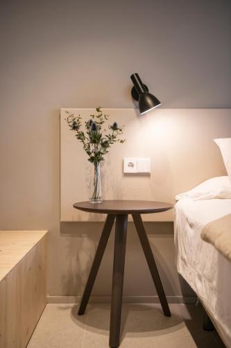 a vase of flowers on a table next to a bed at APARTAMENTS LA CARPA in Banyoles